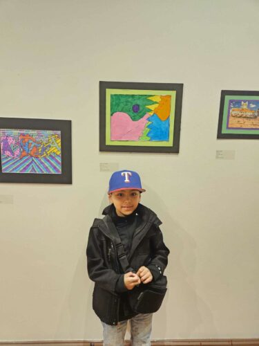 Luis poses near his artwork at the Winter Art Garden